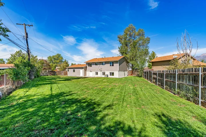Expansive grassy backyard featuring a detached garage with a white door and a wood fence