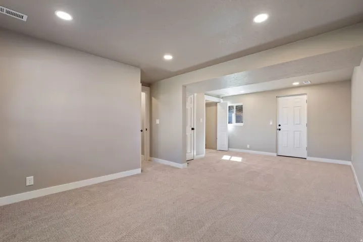 Recessed lighting illuminates neutral-toned walls and plush carpeting, complemented by white trim