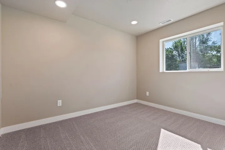 Recessed lighting, neutral wall paint, carpet flooring, and a large window