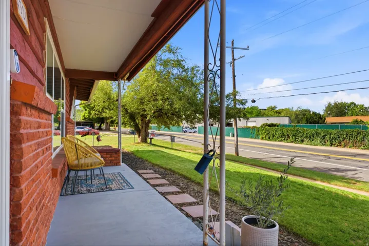 Covered porch featuring a red brick facade, concrete flooring, and decorative metal support columns
