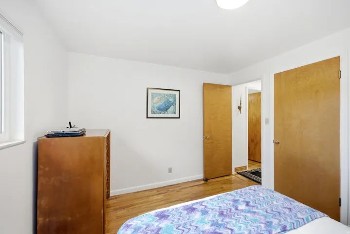 Hardwood flooring, painted white walls, recessed ceiling lighting, and a white-framed window