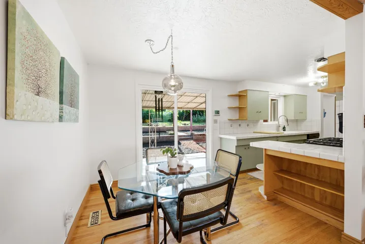 Wood-finish flooring throughout, featuring a glass-top dining table under a pendant light fixture