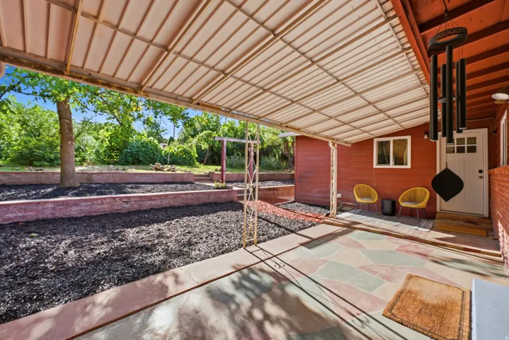 Covered patio with corrugated metal roofing, patterned concrete flooring, and an exterior door