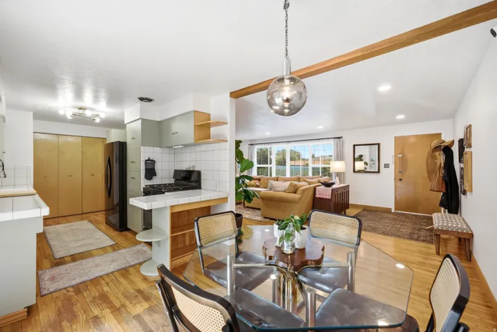 Wood-finish flooring throughout, with a kitchen featuring a tile backsplash and integrated appliances