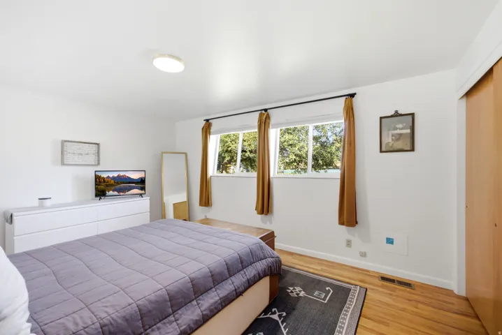 White walls with light-toned wood-finish flooring, featuring a pair of windows and a flush-mount ceiling light