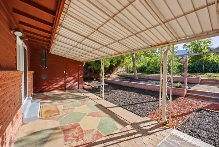 Covered patio featuring a decorative concrete floor and brick accents