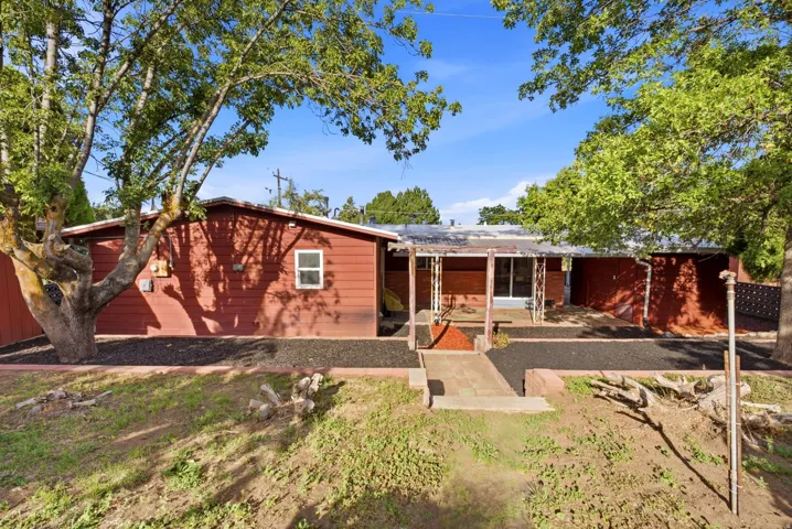 Red siding exterior with a covered porch and mature trees