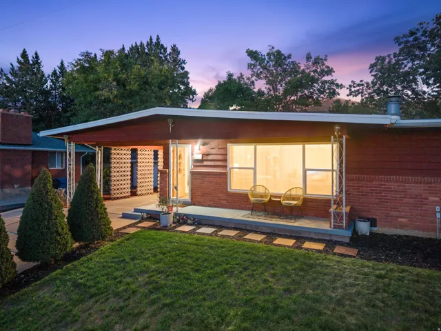 Brick facade with expansive front windows, a covered entry, and a concrete patio
