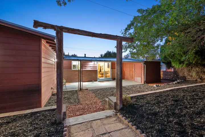 Outdoor space featuring a decorative wood archway, a flagstone-style pathway, and landscaped areas with mulch
