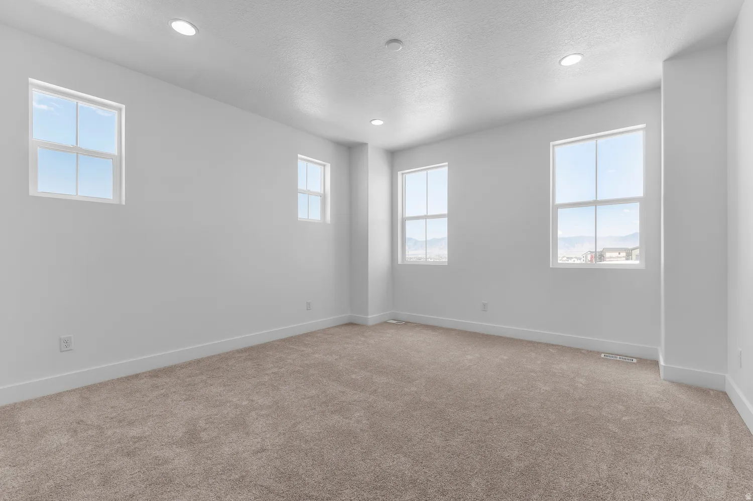 Neutral-toned carpeting, white walls, multiple windows, recessed lighting, and white trim