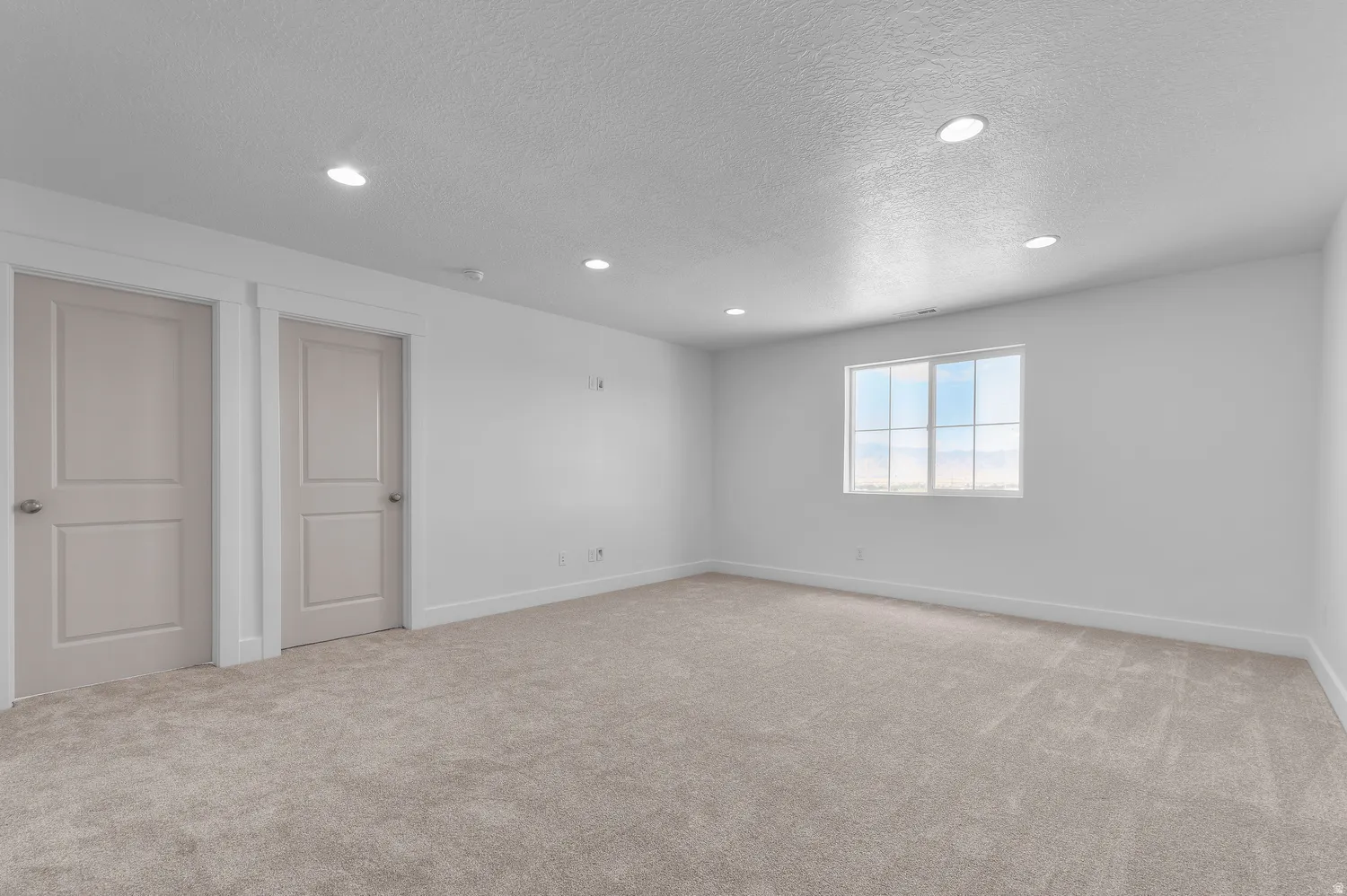 Neutral-toned carpeting, recessed lighting, and a window with white trim