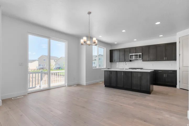 Open concept kitchen featuring dark wood cabinetry, white subway tile backsplash, stainless steel appliances, and a central island with a light-toned countertop