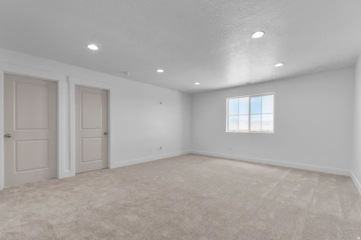 Neutral-toned carpeting, recessed lighting, and a window with white trim
