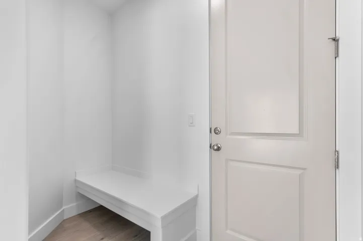 Built-in white bench seating, paneled door with satin nickel hardware, and wood-finish flooring