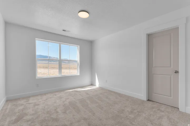 Neutral-toned carpeting, white walls, and a window with a distant mountain backdrop