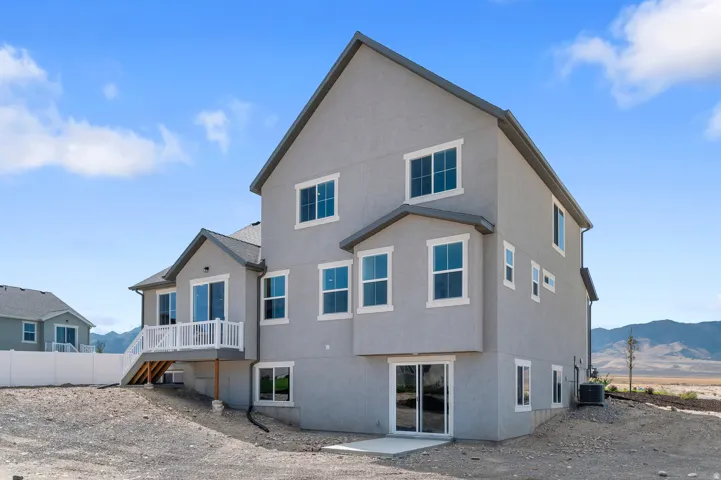 Stucco exterior with multiple windows, featuring a second-story balcony with white railing, and a ground-level sliding glass door