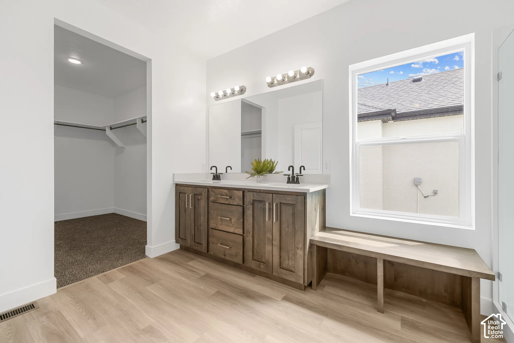 Dual vanity with dark wood-finish cabinetry, white stone-finish countertop, and black fixtures