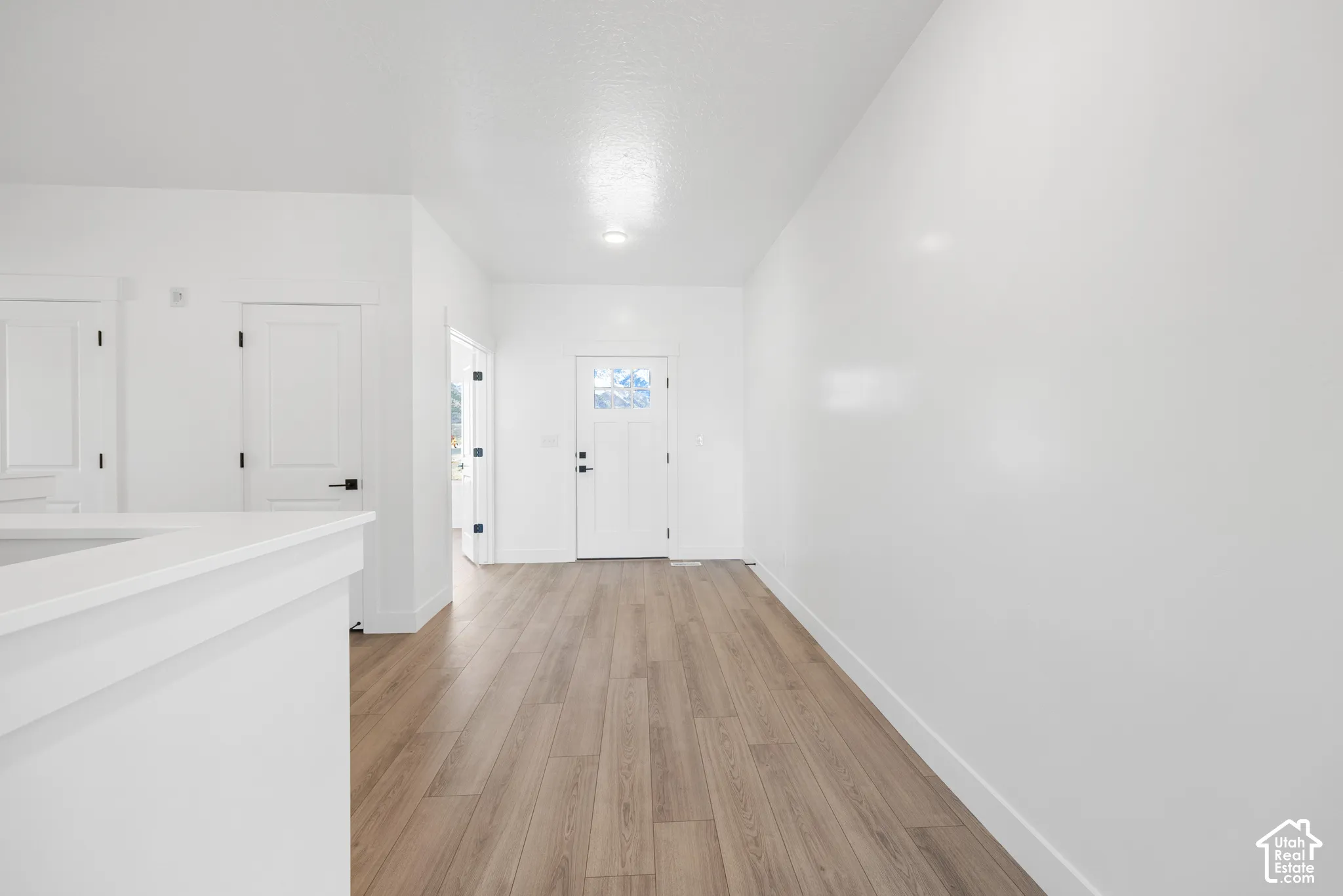 Light wood-finish flooring extends through this open-concept space, complemented by crisp white walls and white trim