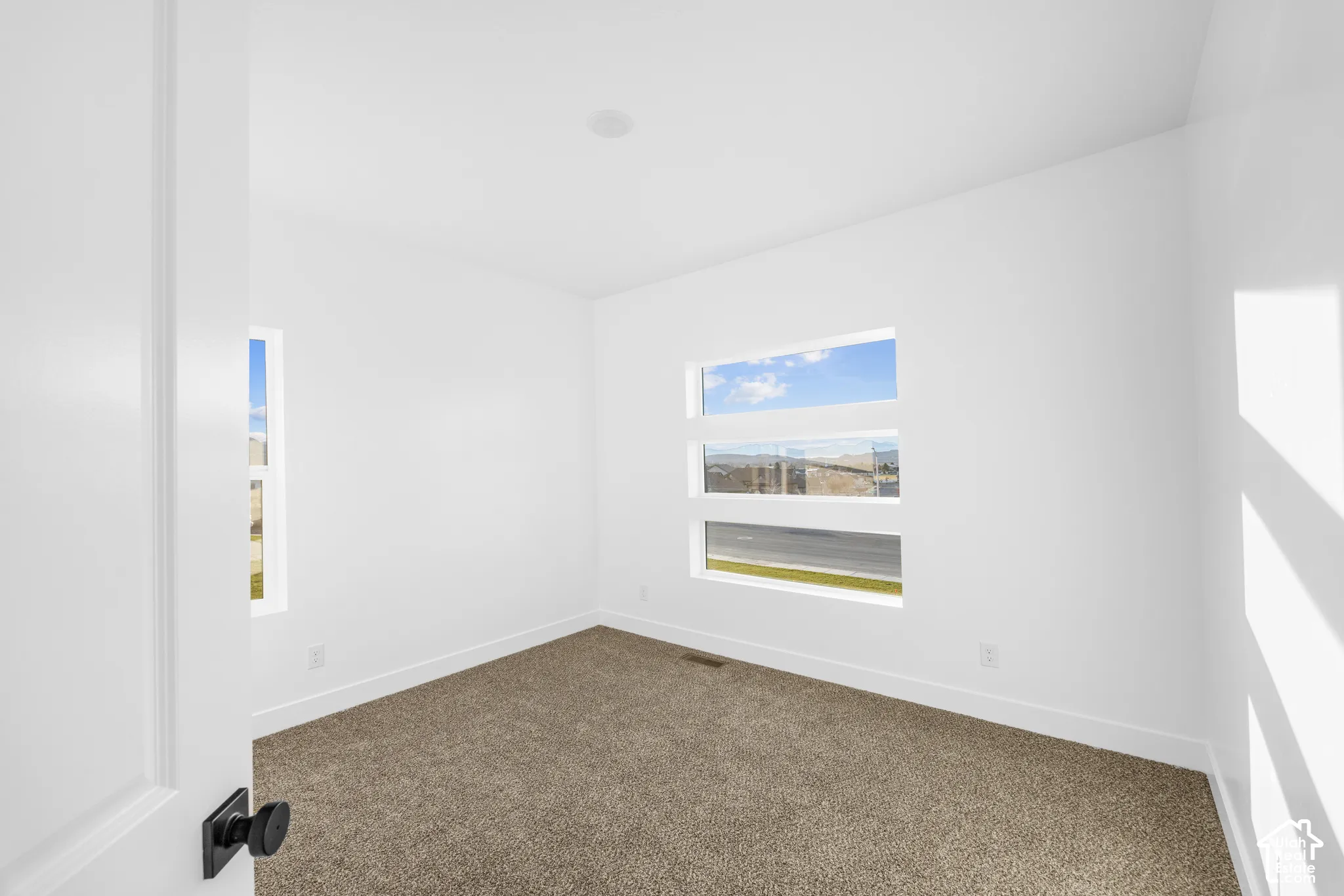 White interior walls with a recessed ceiling light, carpeted flooring, and multiple horizontal windows