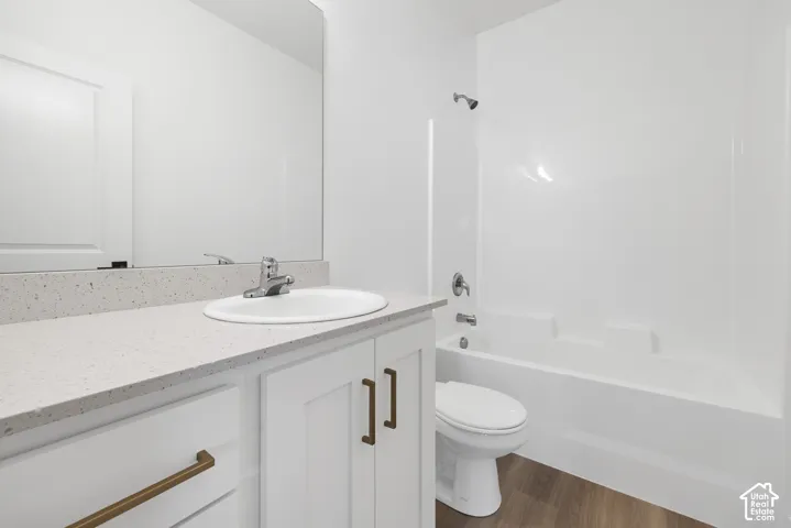 Bathroom featuring a white vanity with bronze hardware, a white undermount sink, a light-toned speckled countertop, and a white tub/shower combination