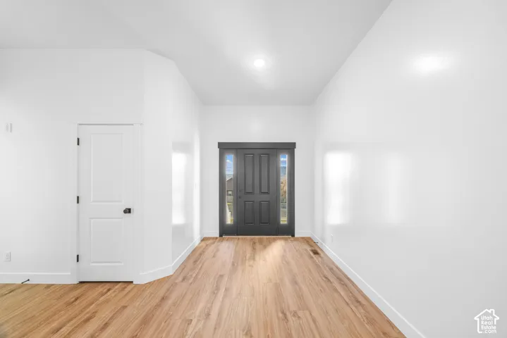 Wood-finish flooring, white walls, and recessed lighting highlight this entry space