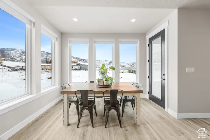 Recessed lighting illuminates wood-finish flooring and multiple tall windows