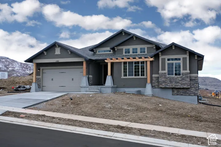 Modern stucco exterior with stone accents, an attached garage, and a decorative pergola over the entry