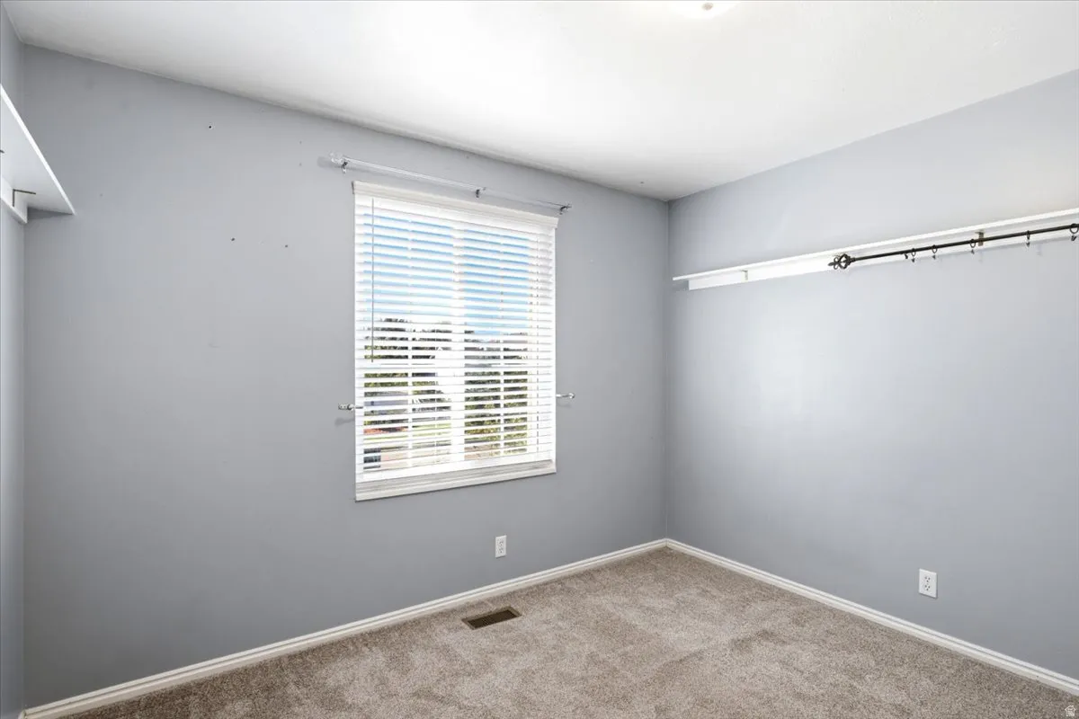 Neutral wall color, carpet flooring, window with blinds, and built-in shelving