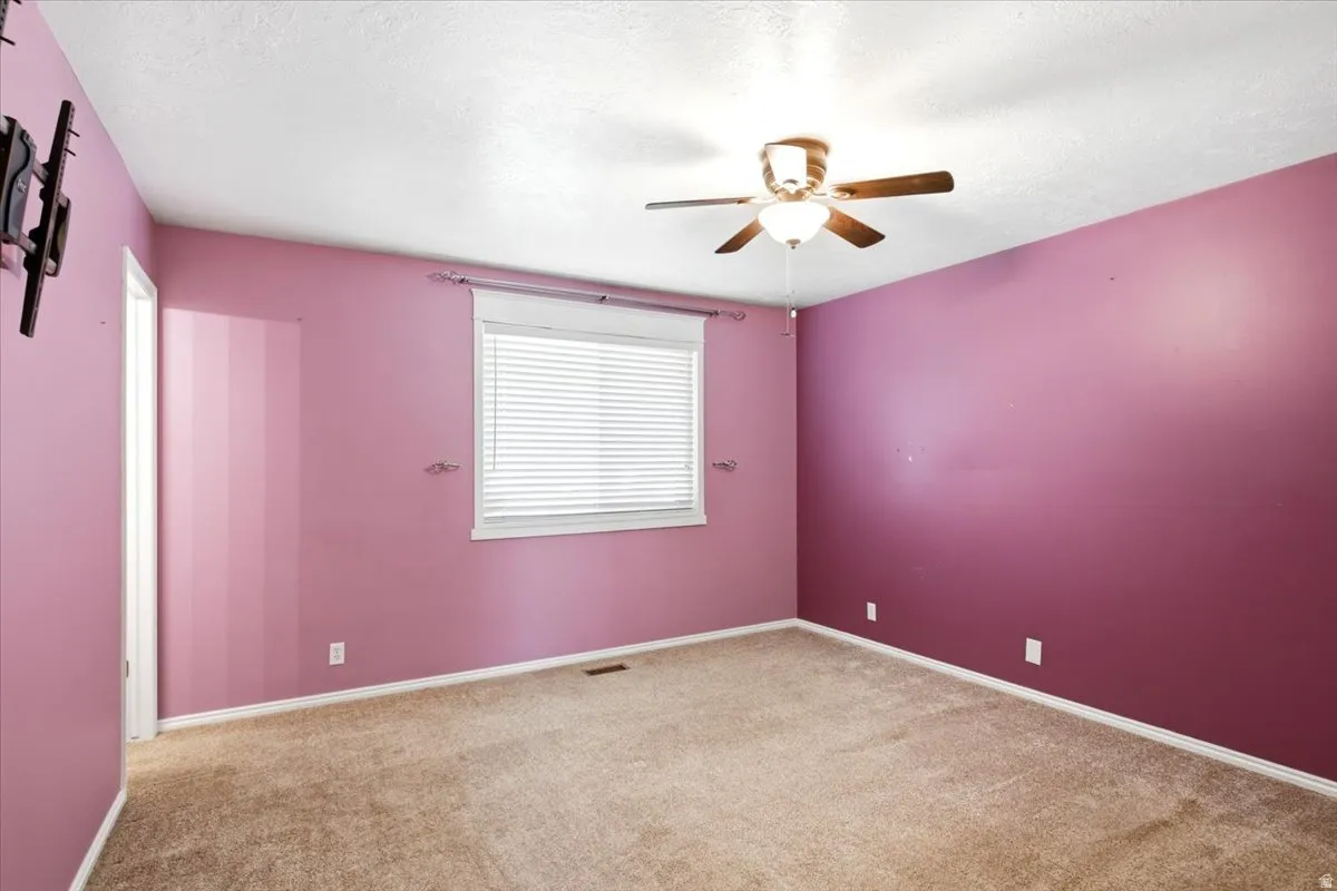 Window with horizontal blinds, overhead ceiling fan with light fixture, wall-to-wall carpeting, and painted walls