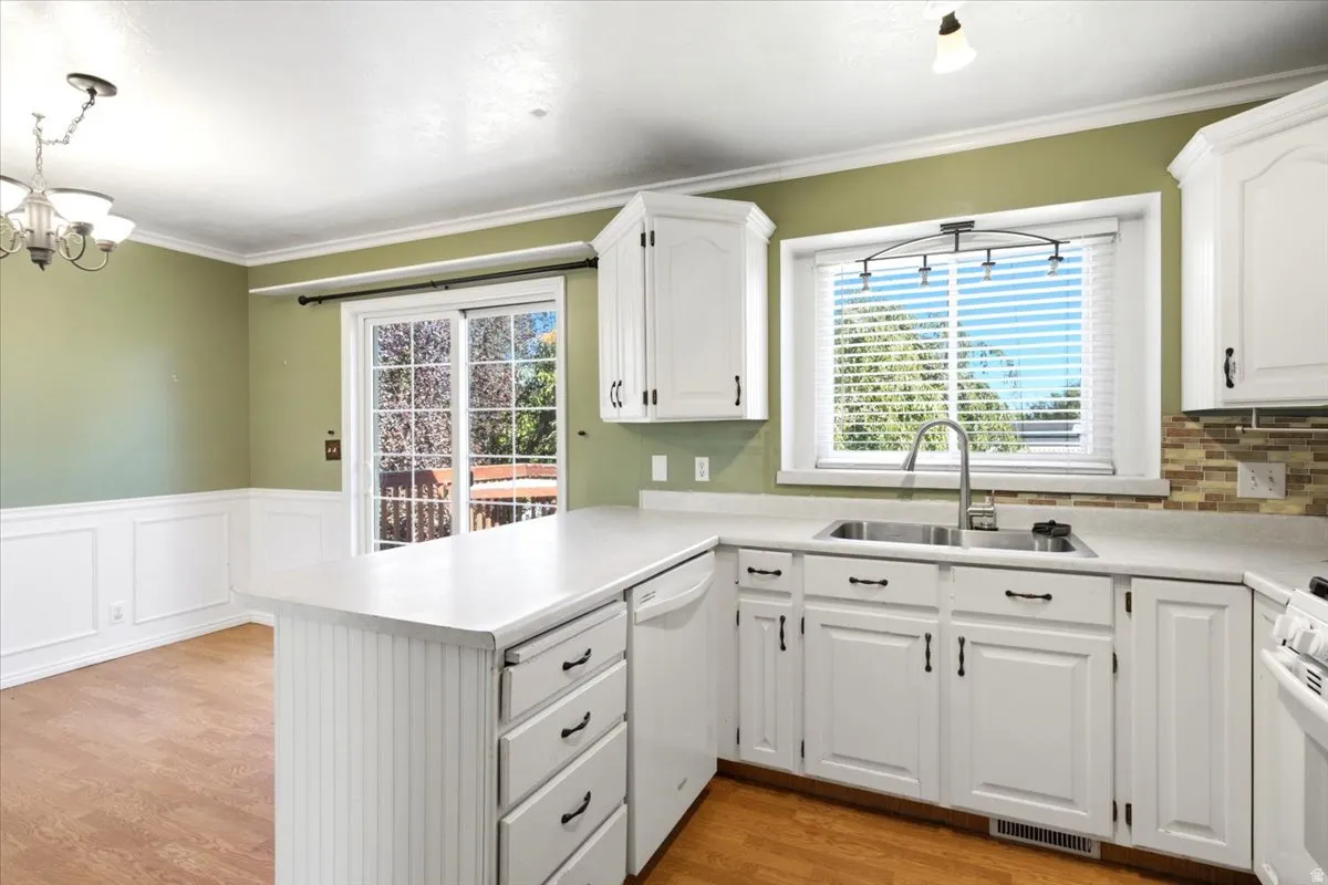 White cabinetry with dark hardware, a dual-basin sink, and a tiled backsplash
