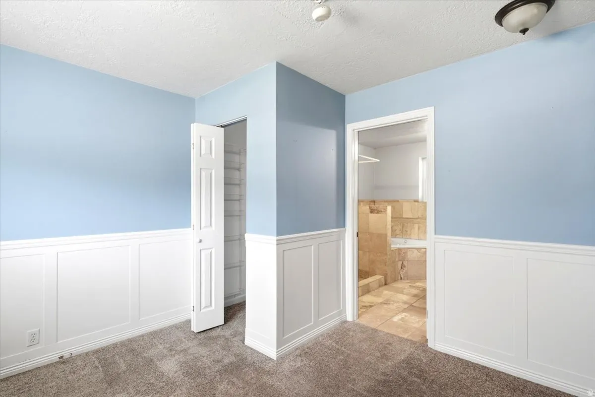 Paneling on lower walls, carpeted flooring, and a built-in closet with shelving