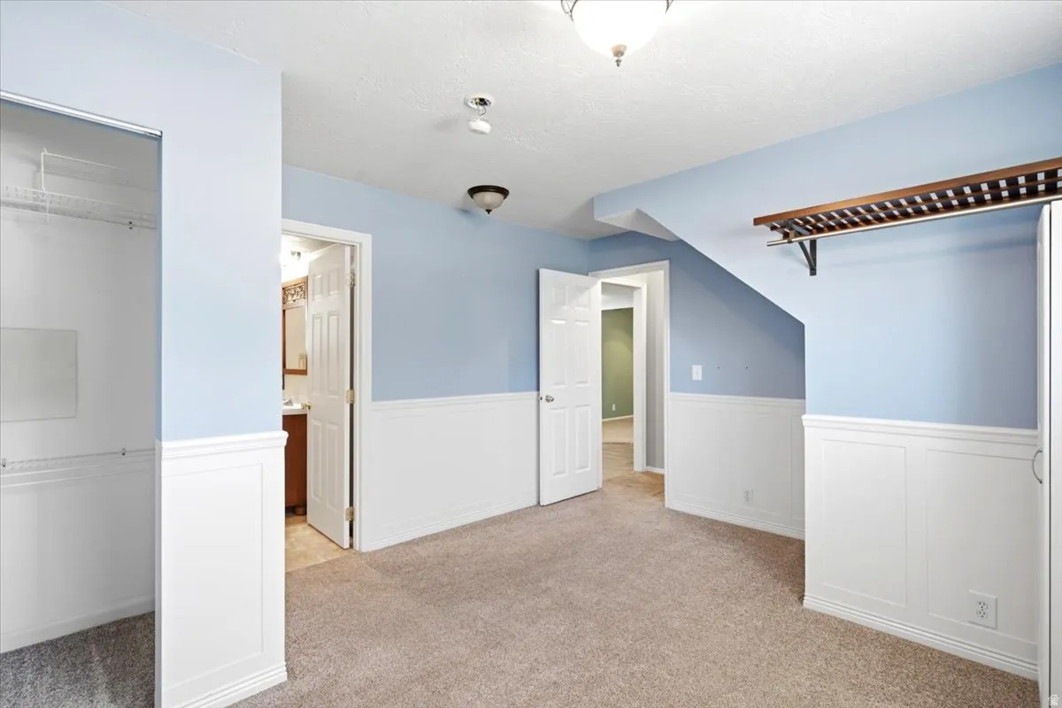 Carpeted room with wainscoting, light blue walls, and a built-in closet with shelving