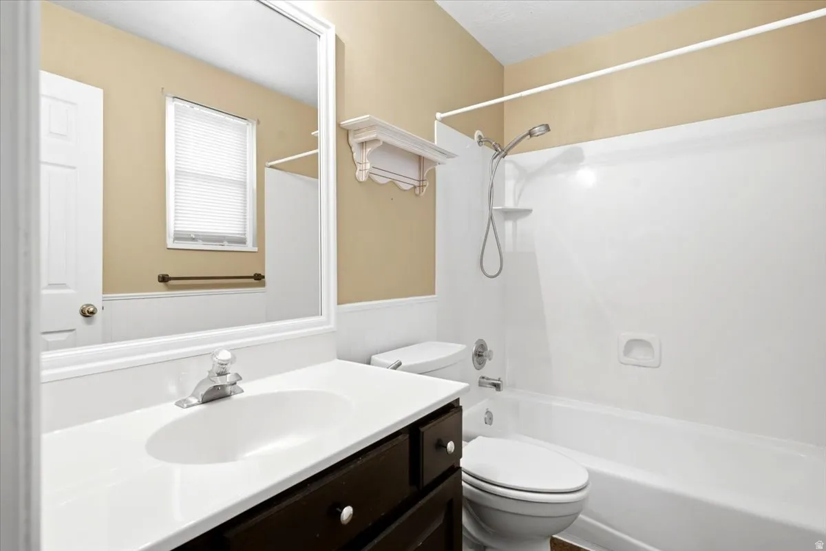 Full bathroom featuring a single vanity with dark wood-finish cabinetry, a white countertop with an integrated sink, a framed wall mirror, and a combination shower and bathtub