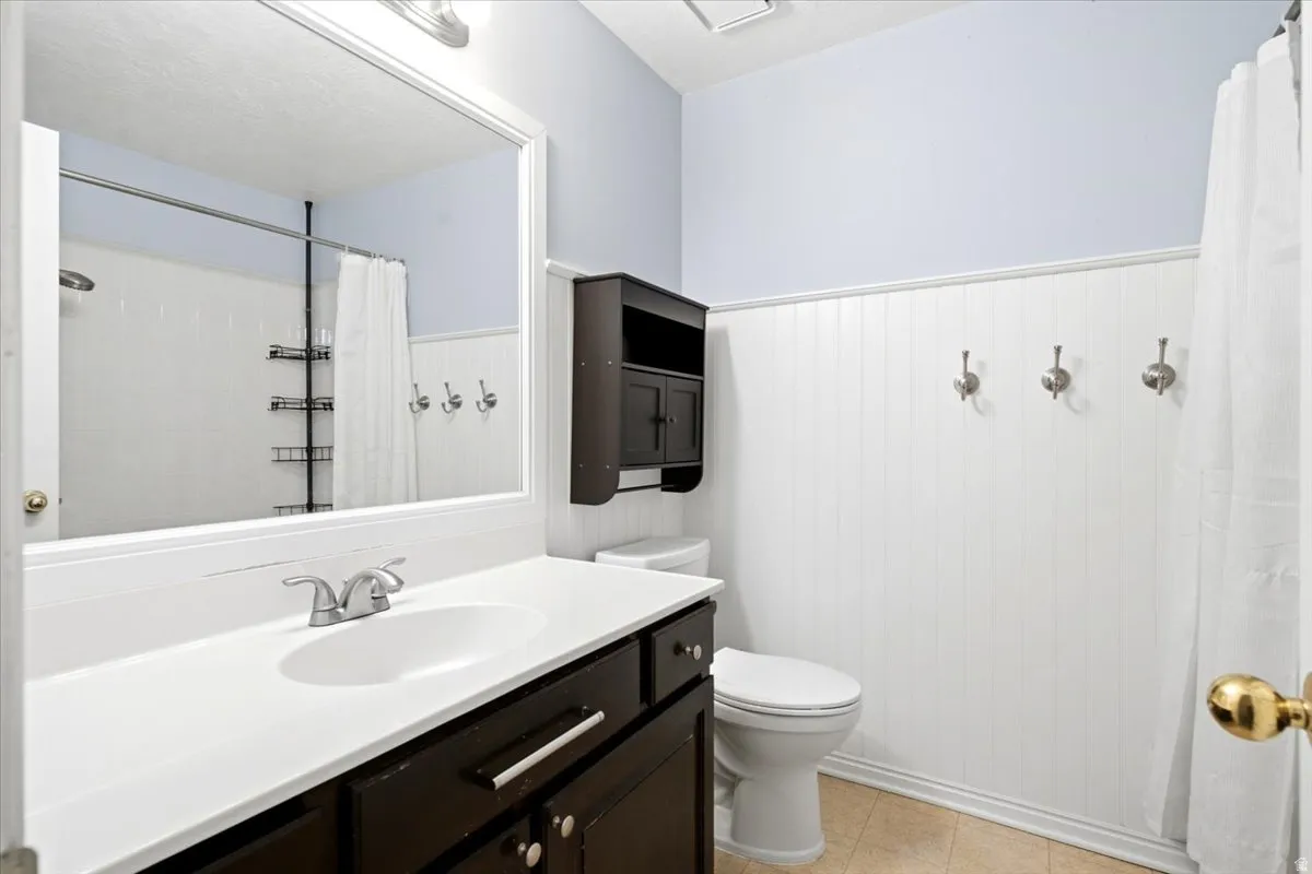 Dark wood-finish vanity with an integrated sink, polished chrome faucet, white countertop, and white wainscoting
