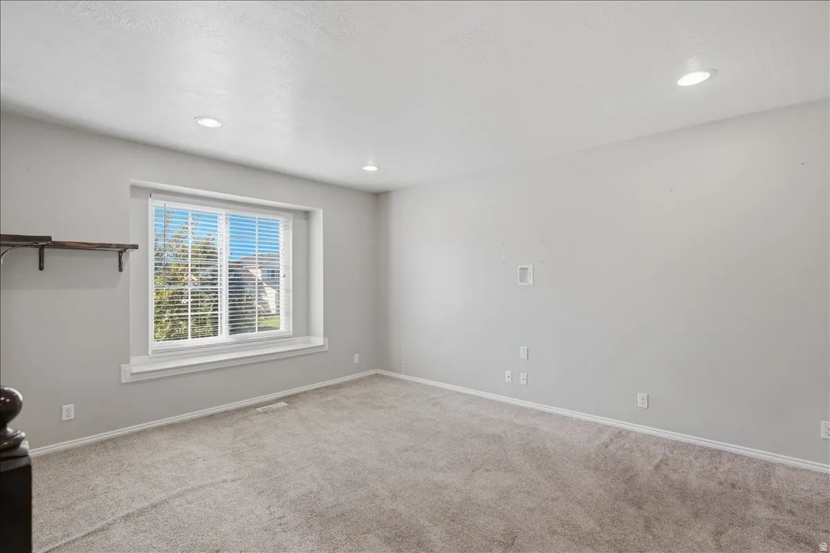 Recessed lighting, light gray wall finish, window with white blinds, white trim, and plush carpeting