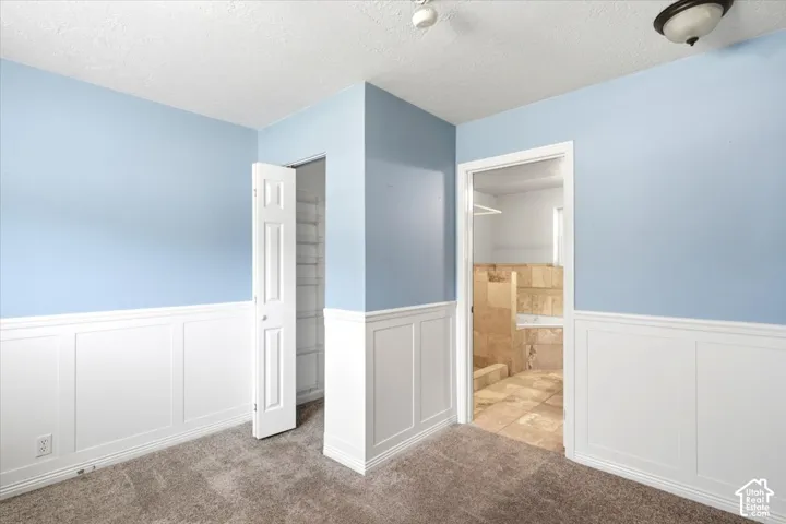 Paneling on lower walls, carpeted flooring, and a built-in closet with shelving