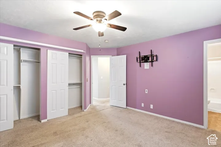 Plush carpet flooring, ceiling fan, white paneled doors, and dual sliding closet doors