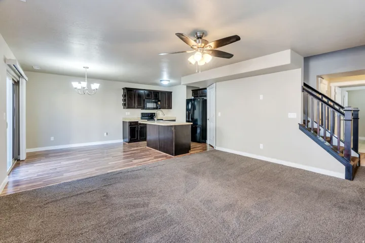 Open-concept living space featuring wood-finish flooring, dark wood cabinetry, a central island, and a built-in staircase