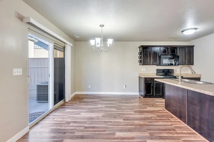Wood-finish flooring throughout, dark wood cabinetry, and a kitchen island with integrated sink