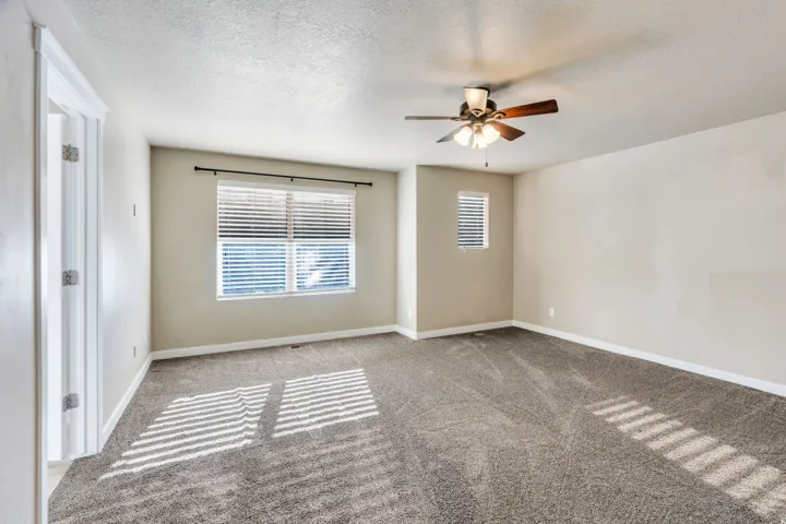 Plush carpeting, window blinds, ceiling fan with integrated lighting, and neutral wall tones