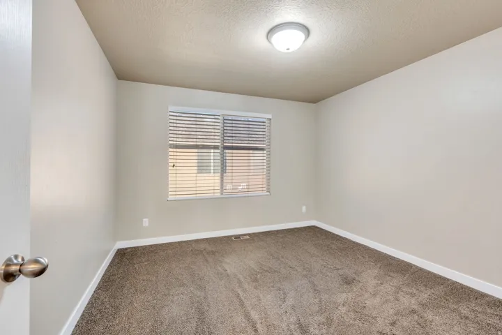 Neutral wall paint, textured ceiling, flush mount ceiling light fixture, window with horizontal blinds, and carpet flooring
