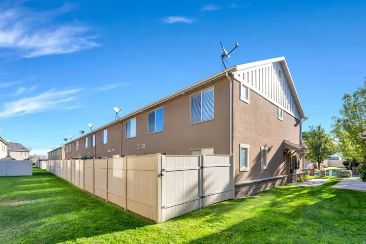 Stucco exterior with white trim, vinyl fencing, and a manicured lawn