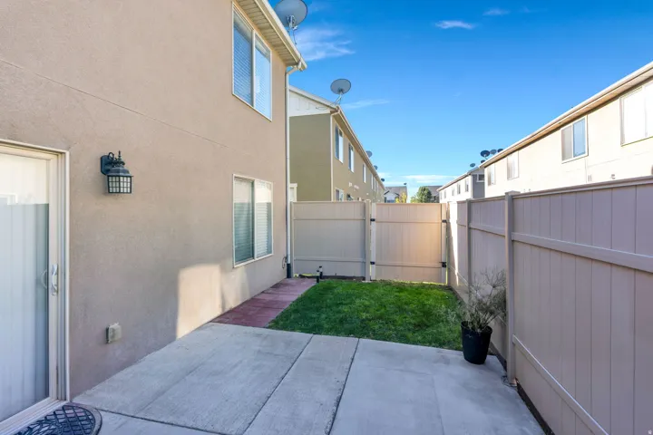 Private outdoor patio with concrete paving, manicured lawn, and perimeter fencing