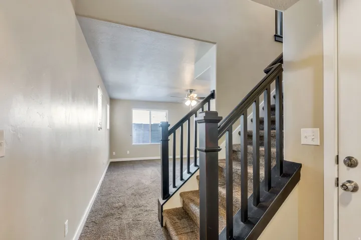 Staircase with dark-finish balusters and newel posts, carpeted treads, and a light-toned interior door