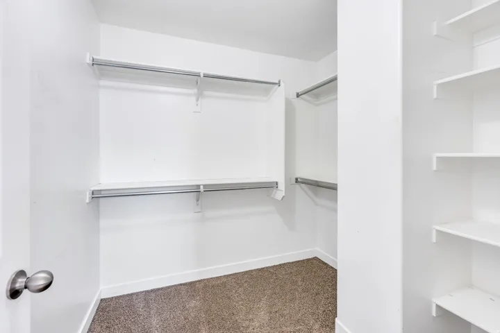 Spacious closet featuring wall-mounted shelving and clothing rods