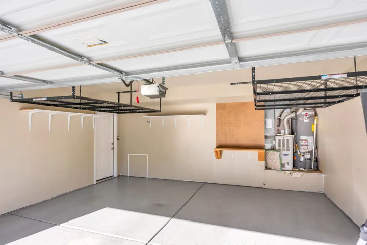 Coated concrete flooring, overhead storage racks, built-in shelving, and a paneled entry door