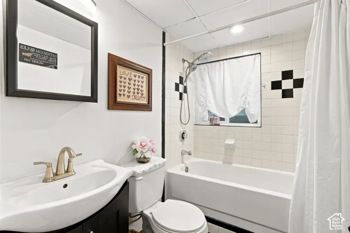 Recessed lighting, tiled shower surround with accent tiles, built-in bathtub, vanity with integrated sink, and bronze-finish faucet
