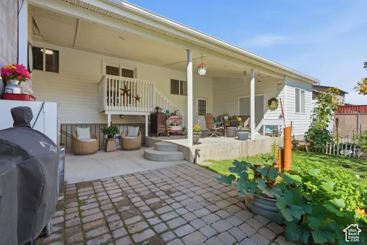 Covered patio area with white siding, a concrete pad, and a wooden deck with railing
