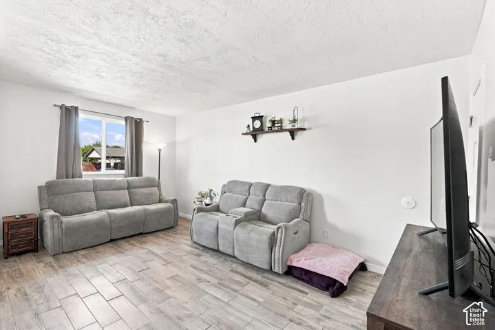 White walls featuring a window with natural light, wood-finish flooring, and a ceiling light fixture