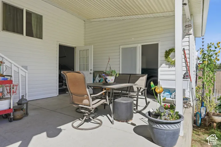 Expansive covered patio with concrete flooring, white vinyl siding, and a white railing